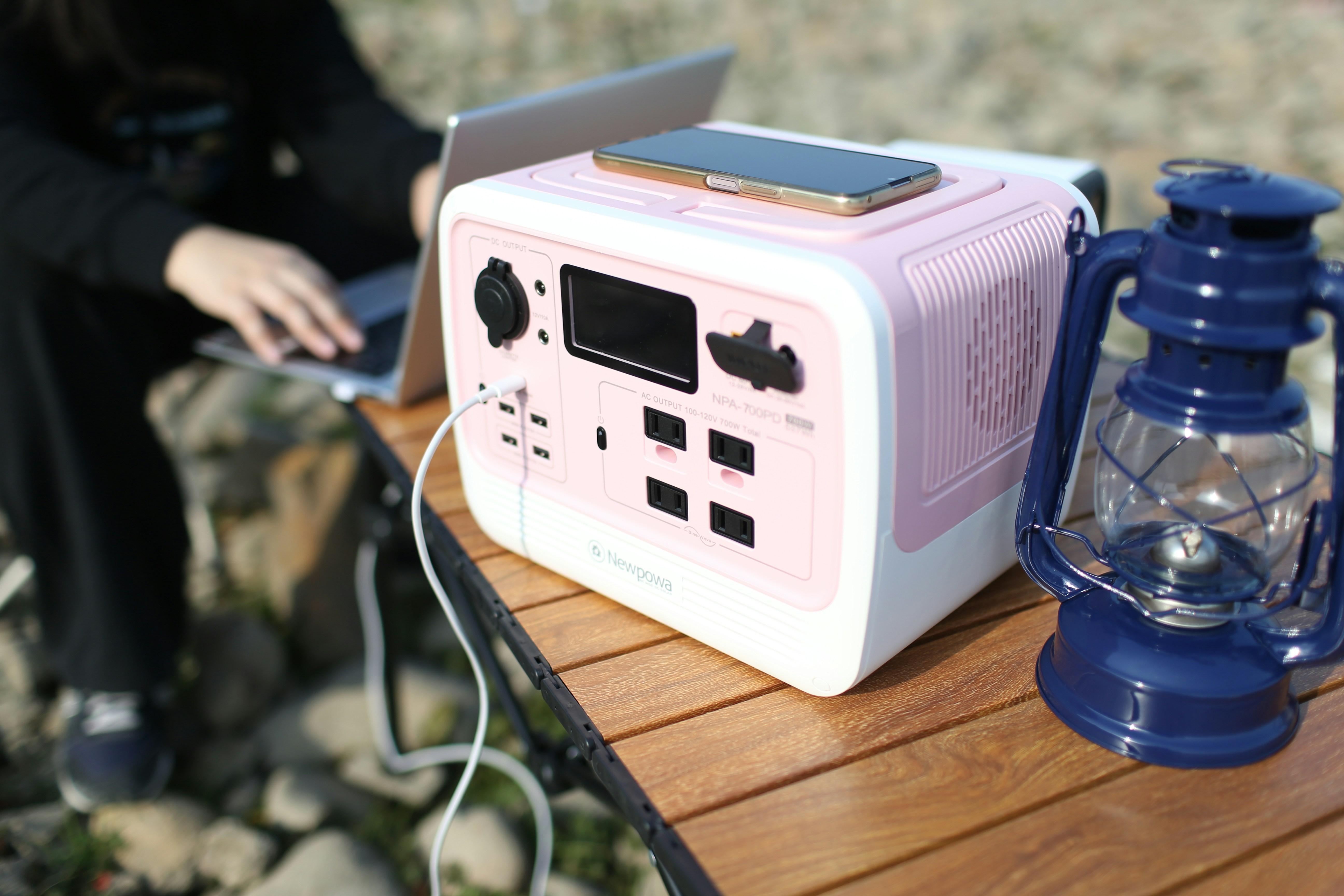 A portable power station charging a phone at a scenic campsite.